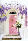 A charming, sunlit doorway is transformed into a gentle celebration, reminiscent of a peaceful side street near Queen's Park itself. The front door, painted a soft, inviting pink with a slightly chalky finish, forms the warm focal point of the scene. Overhead, generous sprays of wisteria drape in cascading garlands, each strand rich with clusters of lavender and lilac blossoms that sway visually like fragrant curtains. The whitewashed walls around the door are calm and understated, their lightly textured surface catching the soft interplay of light and shadow from the trailing vines. A matching pastel shutter sits nearby, quietly echoing the door's pink and tying the whole frontage together in a coordinated wash of gentle colour. On the doorstep rests a grey, vintage-style florist's bucket, its metal sides subtly worn as if it has travelled from local markets along Salusbury Road. It is filled to the brim with sumptuous white and cream roses, each bloom perfectly open so that you can almost trace the spiral of each petal with your fingertips. Tucked among the roses are sprigs of soft green foliage, adding a fresh, leafy contrast that keeps the arrangement from feeling too formal. Around the bucket, a blush pink ribbon is knotted into a relaxed bow, its satin tails resting softly against the stone step like a final, thoughtful flourish. The atmosphere is one of tender anticipation and homecoming, the sort of floral moment a local Queen's Park florist might create to celebrate a first night in a new home, to welcome loved ones to a changed address, or to send a message of support and hope as someone steps into their next chapter.